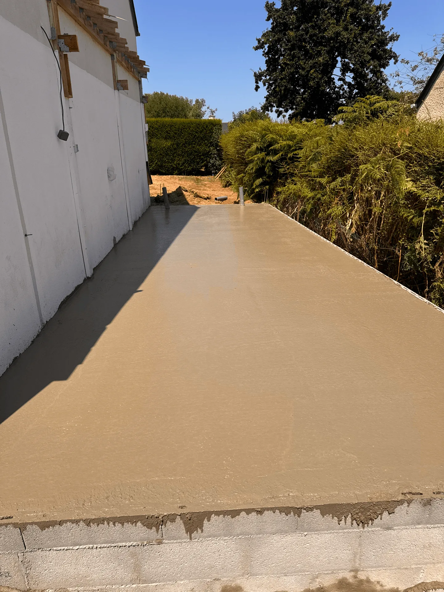 Dalle de béton fraîchement coulée contre une maison