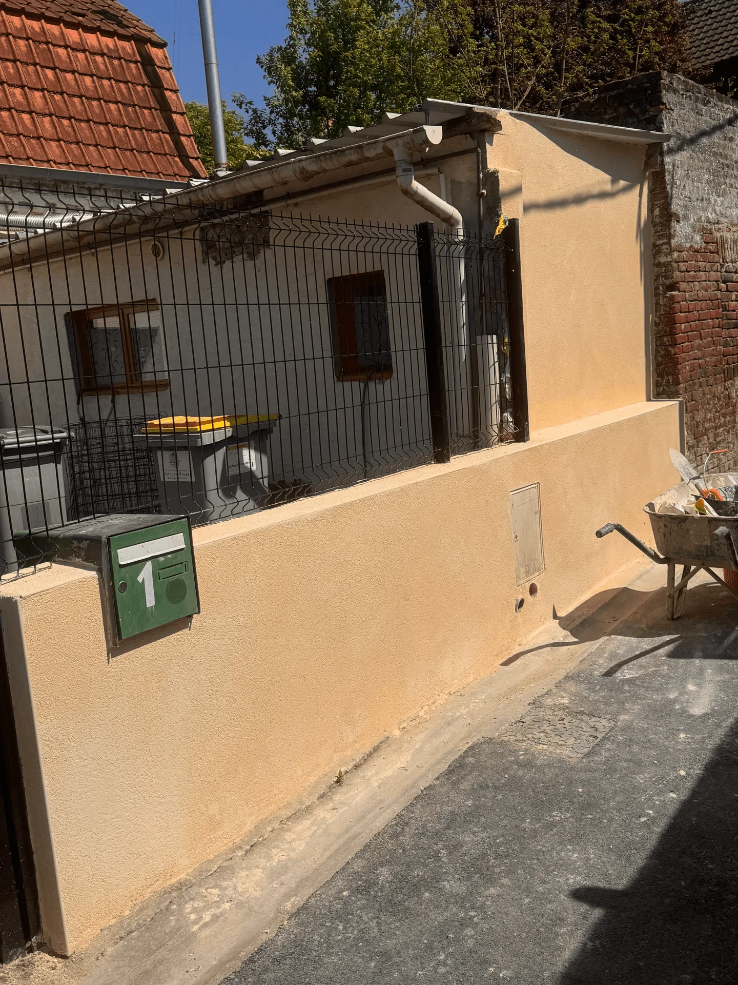 Vue d’ensemble du muret enduit avec matériel de chantier sur place